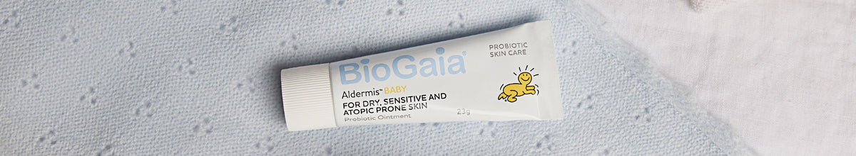 BioGaia Skincare Aldermis Probiotic Ointment tube on a blue textured blanket background.