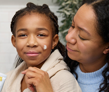 Mom applying on child the BioGaia Probiotic Ointment with live probiotics for babies and children with dry, sensitive and atopic-prone skin  to a child's face with a focus on skincare.