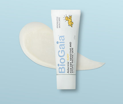 BioGaia Aldermis Probiotic Ointment on light blue background on top of a texture swatch of the ointment with live probiotics for babies and children with dry, sensitive and atopic-prone skin.