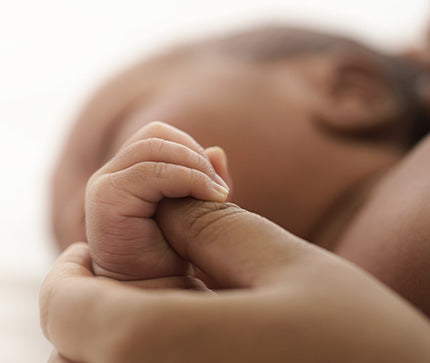Close-up of a baby's hand held by an adult's hand, with a blurred background