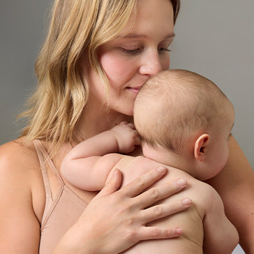 Mother holding a baby against a gray background