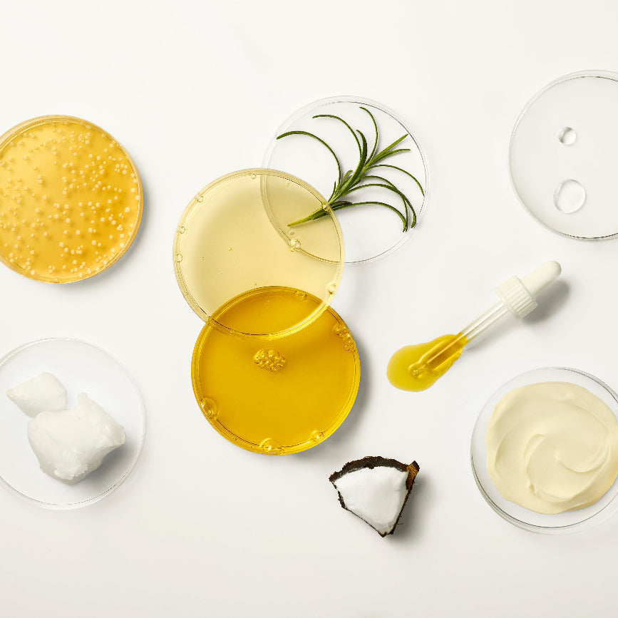 Flat lay of cold-pressed organic oils, cream textures and natural ingredients, including rosemary and coconut oil, shea butter, glycerin, representing the ingredients used across the BioGaia Skincare range.