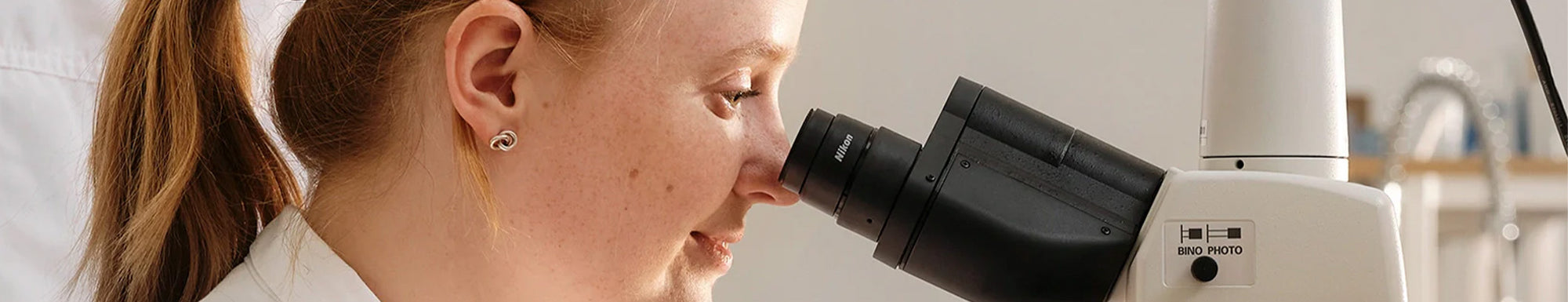 Researcher looking through a microscope, representing BioGaia Skincare’s science-backed approach to delicate skin care.
