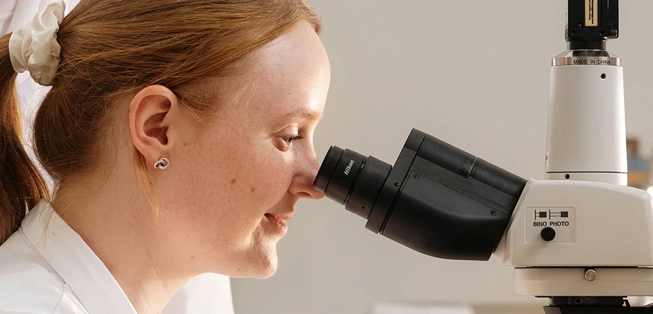 Researcher looking through a microscope, representing BioGaia Skincare’s science-backed approach to delicate skin care.