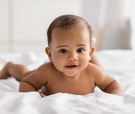 Smiling baby lying on a white blanket with a soft focus background