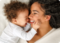 Mother and child lying close together, smiling and interacting.